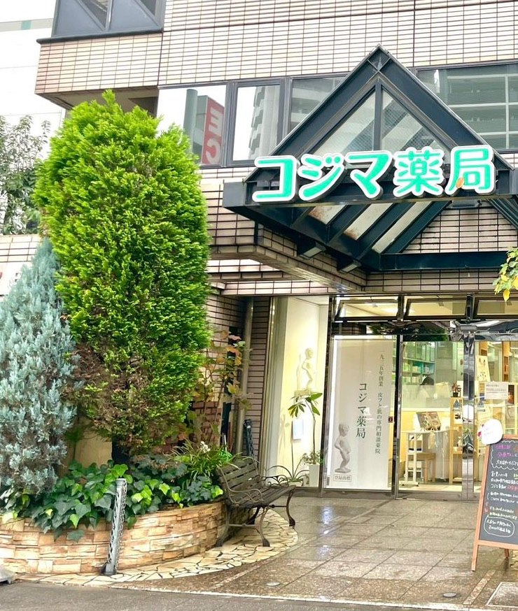 大通り沿いにあるコジマ薬局の外観と入口