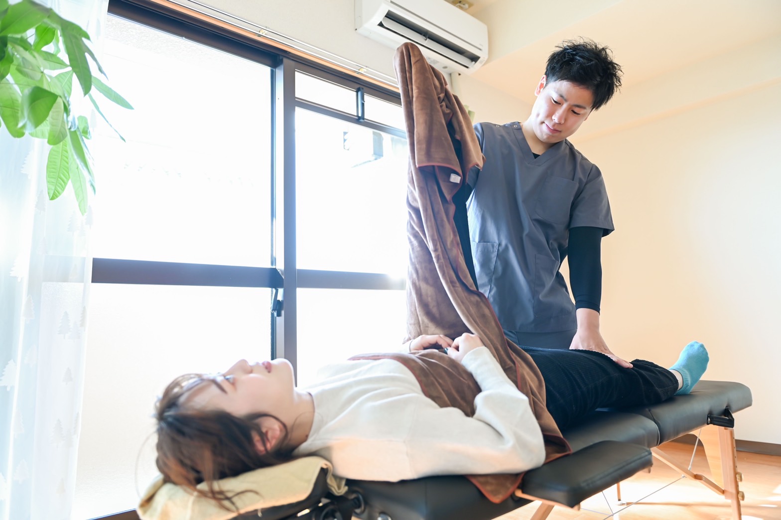 仰向けの患者さんの脚を動かして状態を確認している様子